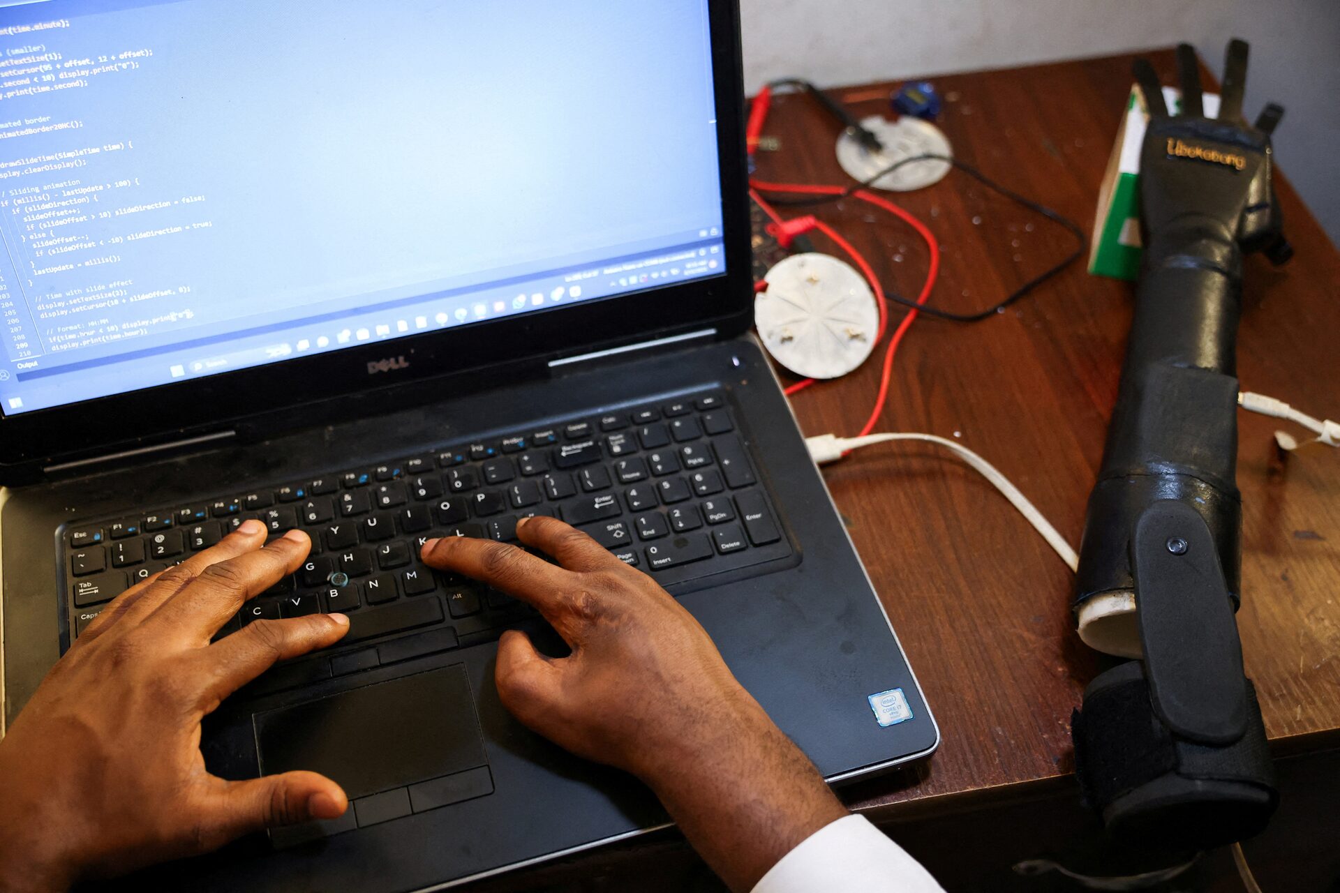 Ubokobong Amanam, 28, who lost a limb, applies code to a bionic arm ready to be made into a prosthesis, which he co-created with his brother John Amanam, 36, a former movie effects artist who creates custom prosthetics that match skin color, at their Immortal Cosmetic Art laboratory in Uyo, Akwa Ibom state, Nigeria, August 15, 2025. REUTERS/Sodiq Adelakun