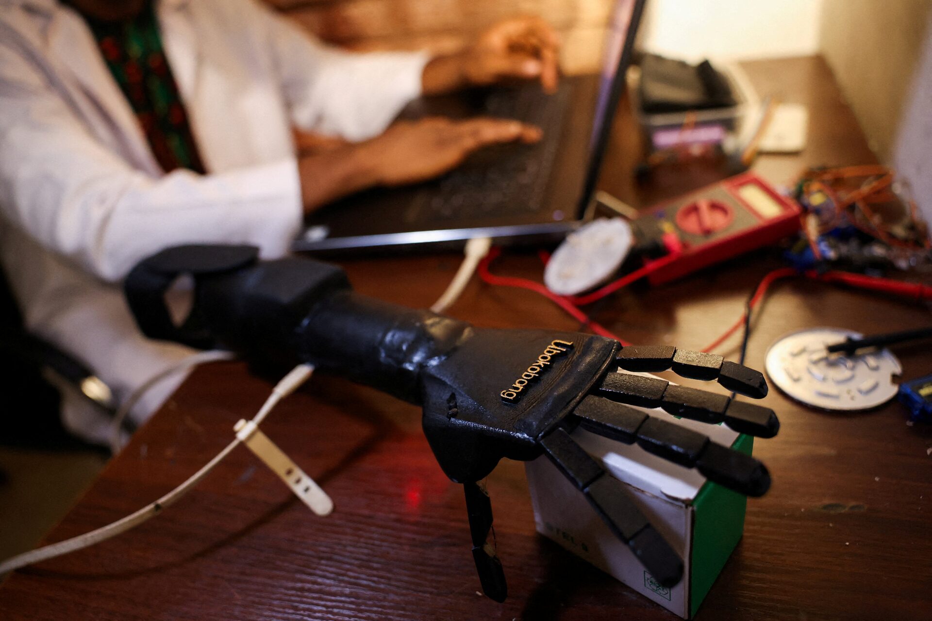 Ubokobong Amanam, 28, who lost a limb, applies code to a bionic arm ready to be made an artificial arm, which he co-created with his brother, John Amanam, a former movie effects artist who creates custom prosthetics that match skin color, at their Immortal Cosmetic Art laboratory in Uyo, Akwa Ibom state, Nigeria, August 15, 2025. REUTERS/Sodiq Adelakun