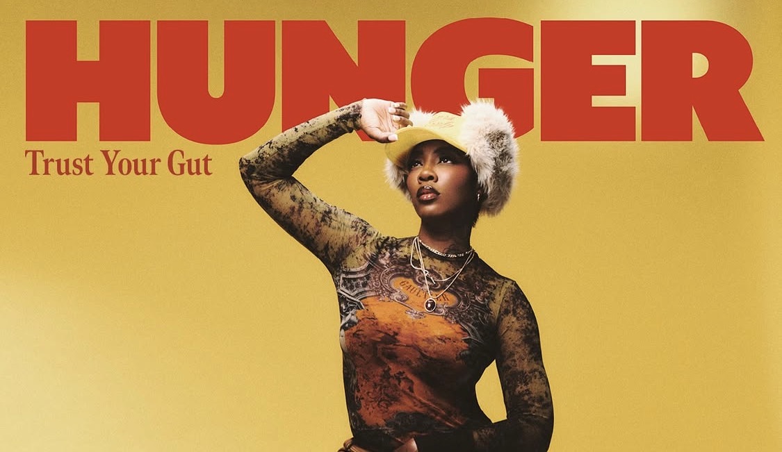 Tiwa Savage wears top by JEAN PAUL GAULTIER, hat by PARALLEL X STUDIO, earrings by ACCESSORIZE, rings by NEXT and shorter necklaces by H&M